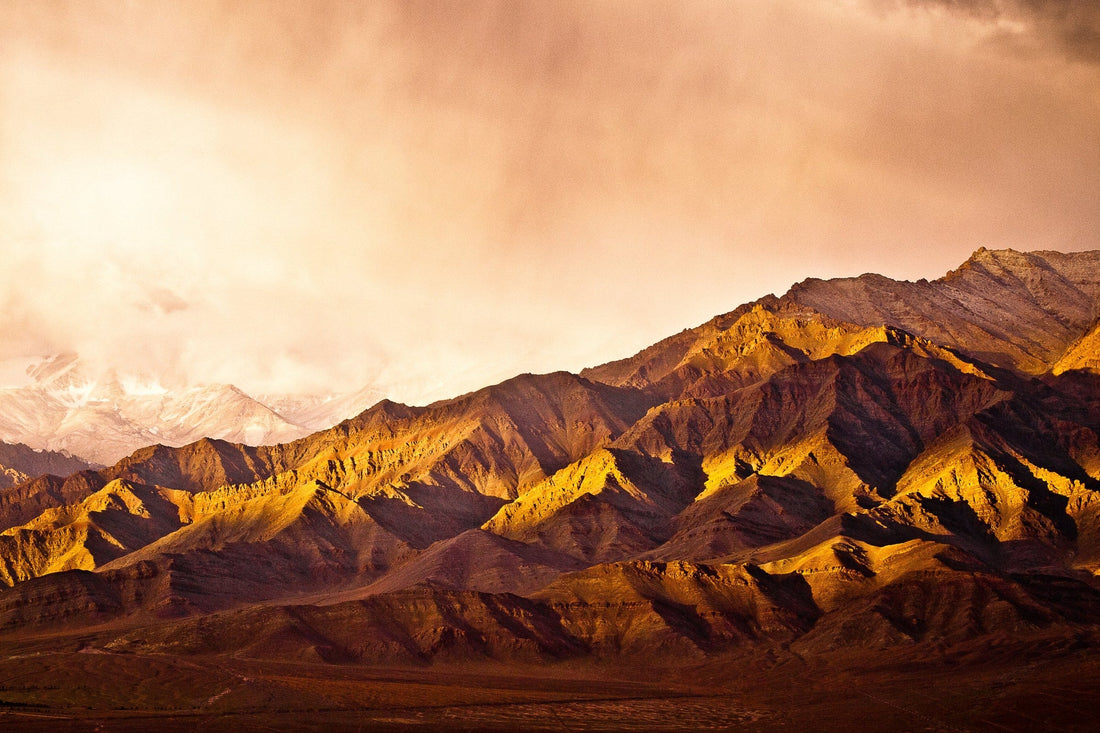 Golden morning light on the ridges of the Zanskar Range under storm clouds, Ladakh, India — fine art photography print by Martin Sojka