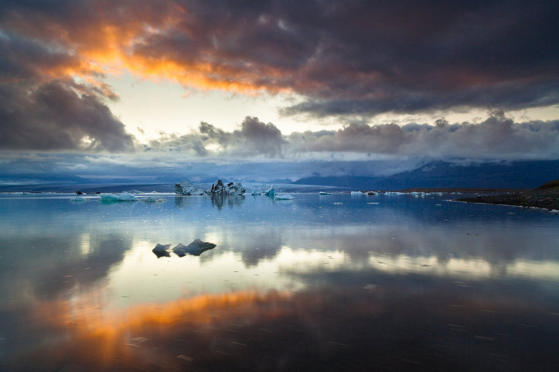 Icebergs and storm clouds glowing orange mirrored in the still water of Jökulsárlón Glacier Lagoon, Iceland — fine art photography print by Martin Sojka
